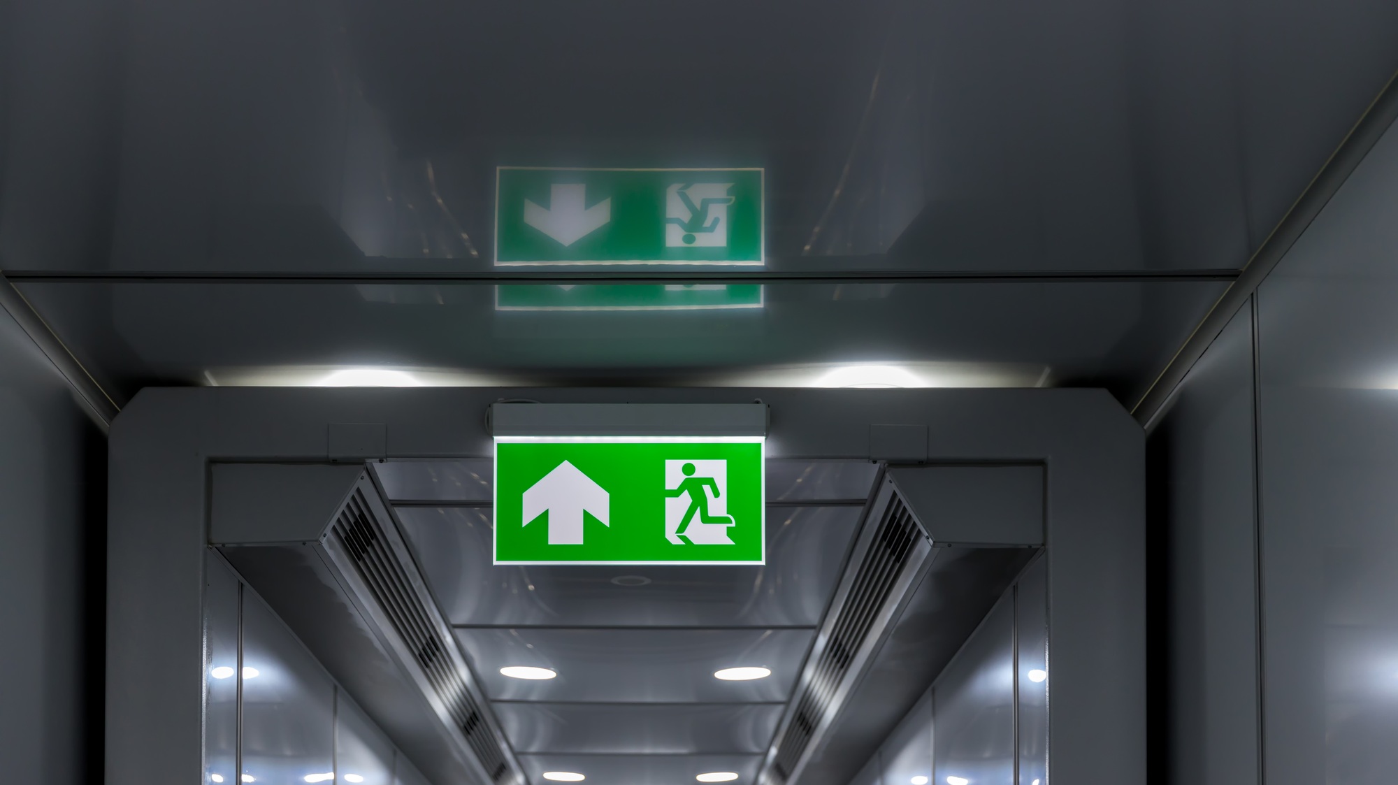 Green emergency exit sign showing the way to escape. Fire exit in the building.